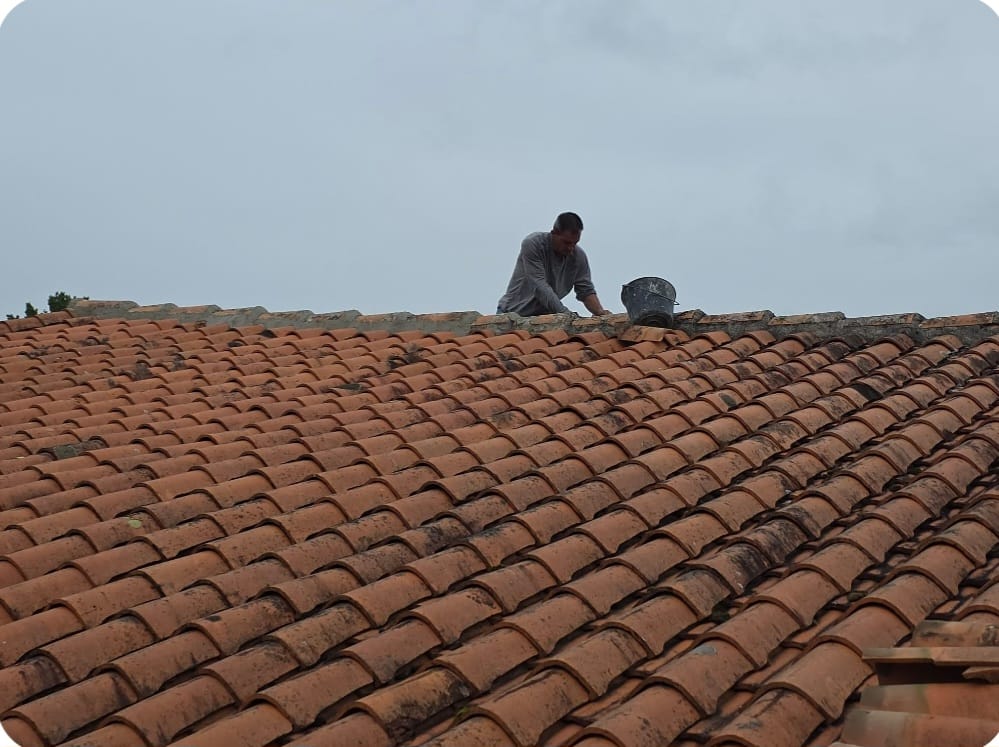 Artisan couvreur inspectant un toit en tuiles en Charente